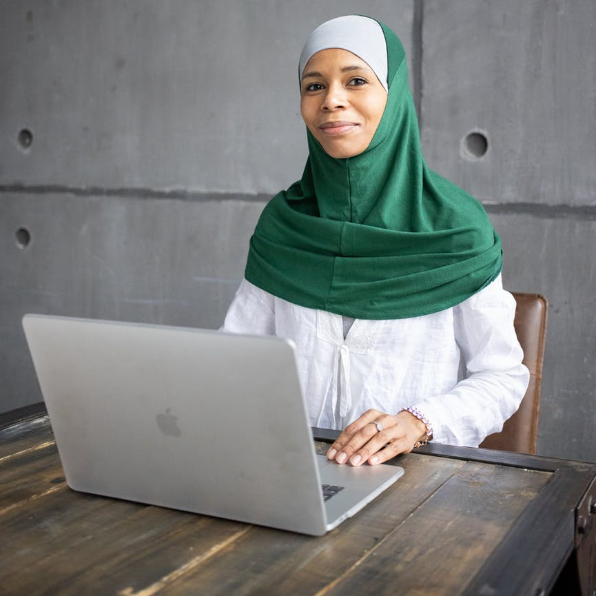 smiling businesswoman using laptop while looking at camera indoors